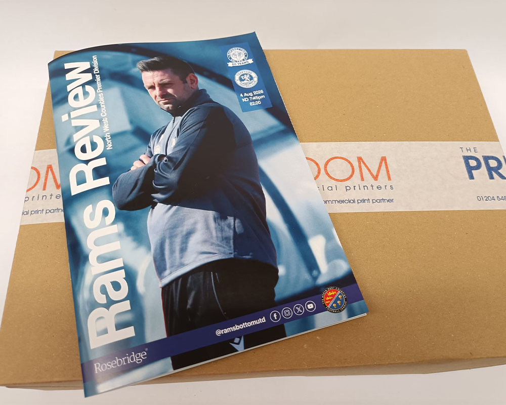 Ramsbottom United FC matchday programme on top of The Print Room's delivery packaging