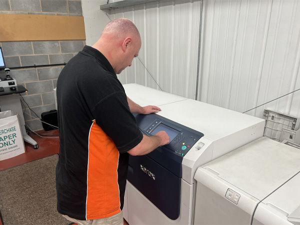 Team member peter configuring industral printing machine prior to quality bound documents.